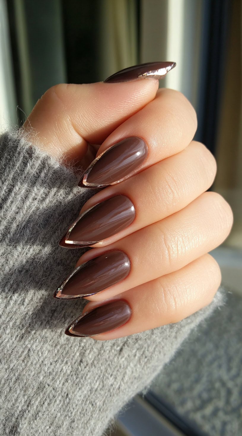 Almond-shaped nails in a rich chocolate tone with subtle chrome outlining the tips.