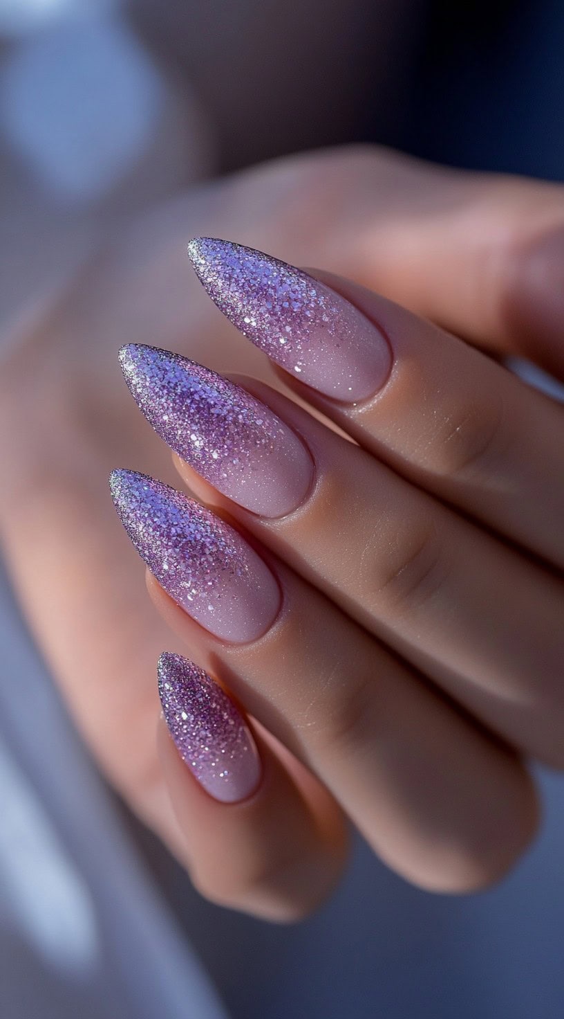 Almond-shaped nails featuring a soft pink-to-purple ombre base covered with a shimmering silver and purple glitter fade.