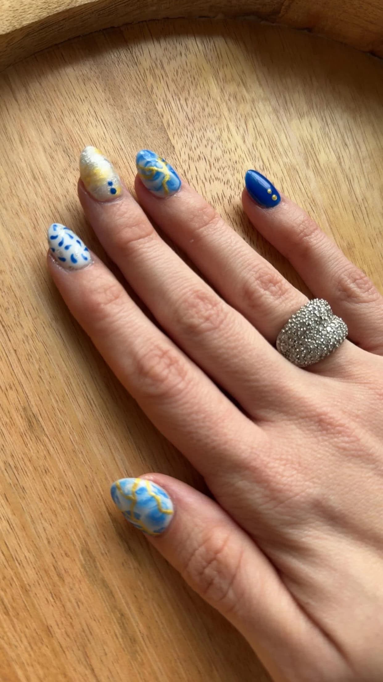 Almond nails for short nail beds featuring bold blue and yellow colors with hand-painted abstract art, ideal for making short nails look longer and more stylish.