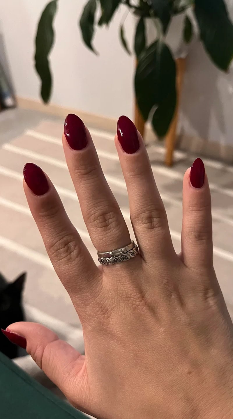 Elegant almond-shaped nails painted in deep red, a flattering choice for small hands.