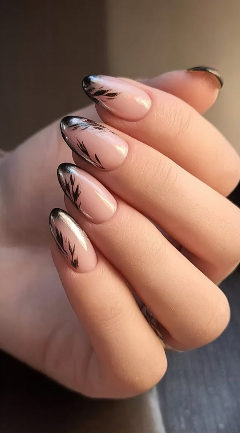 A close-up of almond-shaped nude nails with metallic black feathered French tips that blend into the base.