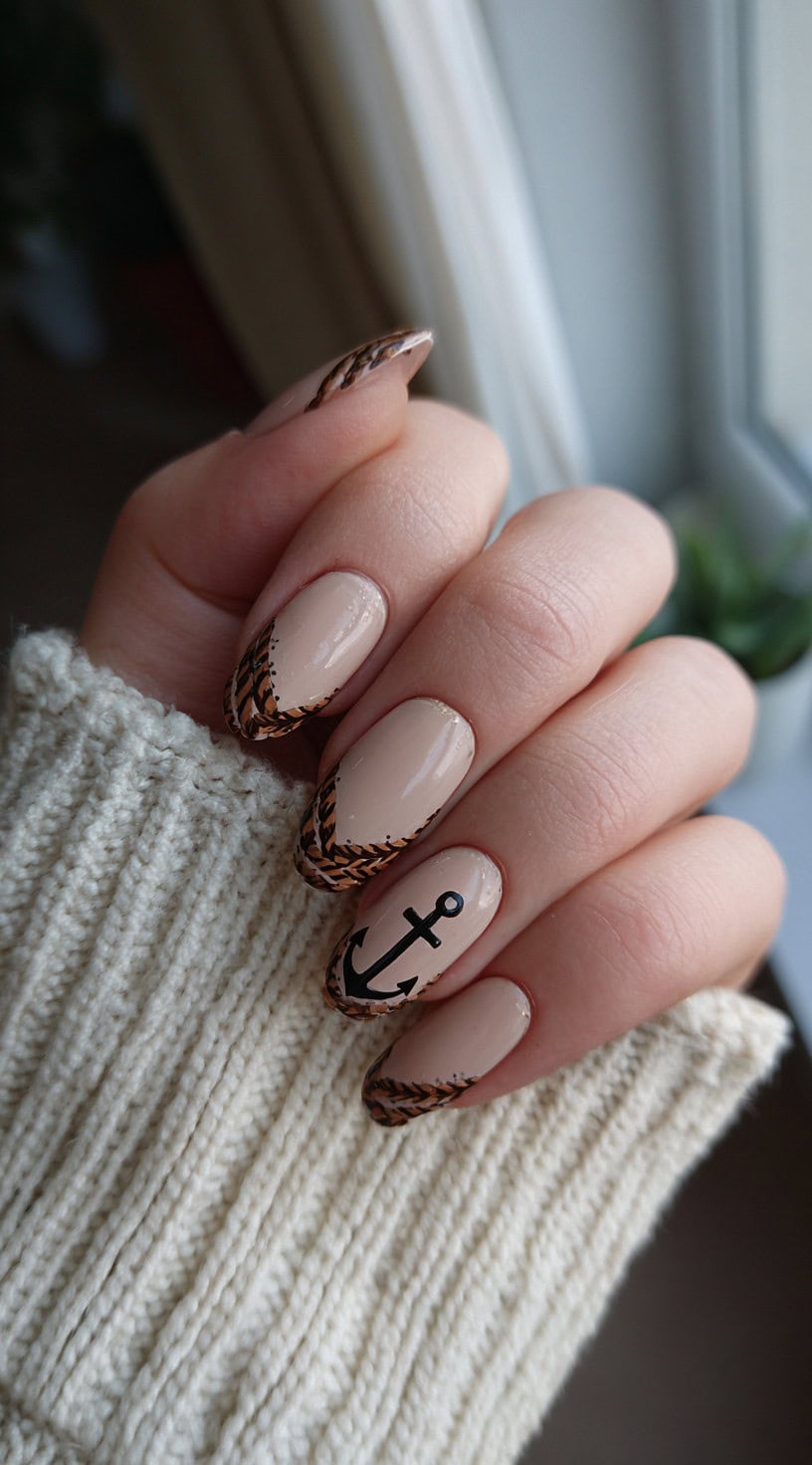Nude almond nails with brown braided rope French tips and an accent anchor decal on the middle finger.