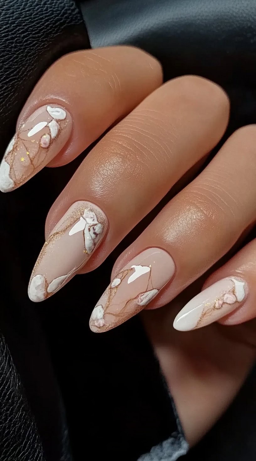Nude almond nails with white petal art and gold marbling throughout each nail.