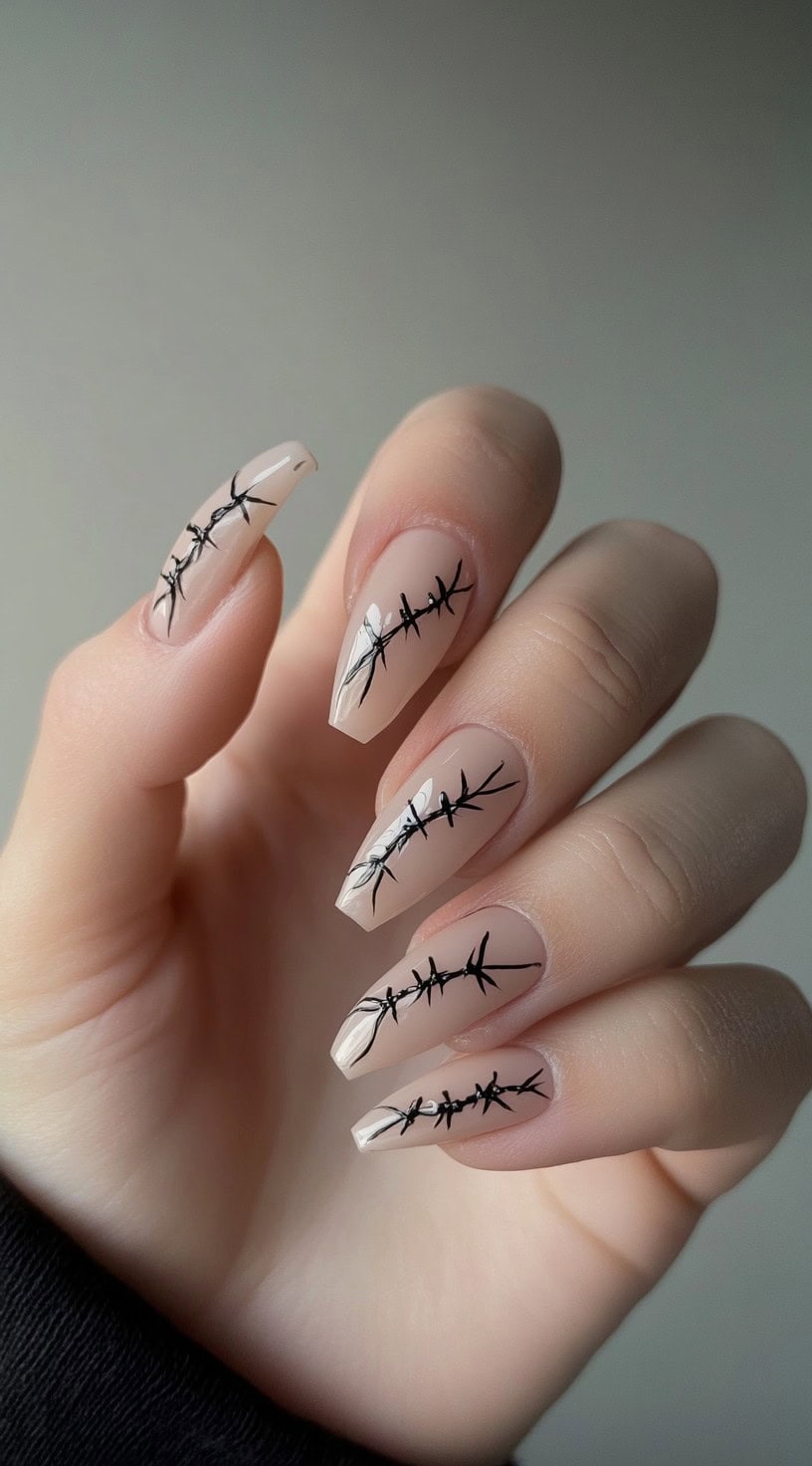 Almond-shaped nude nails with thin black barbed wire nail art running diagonally across each nail.