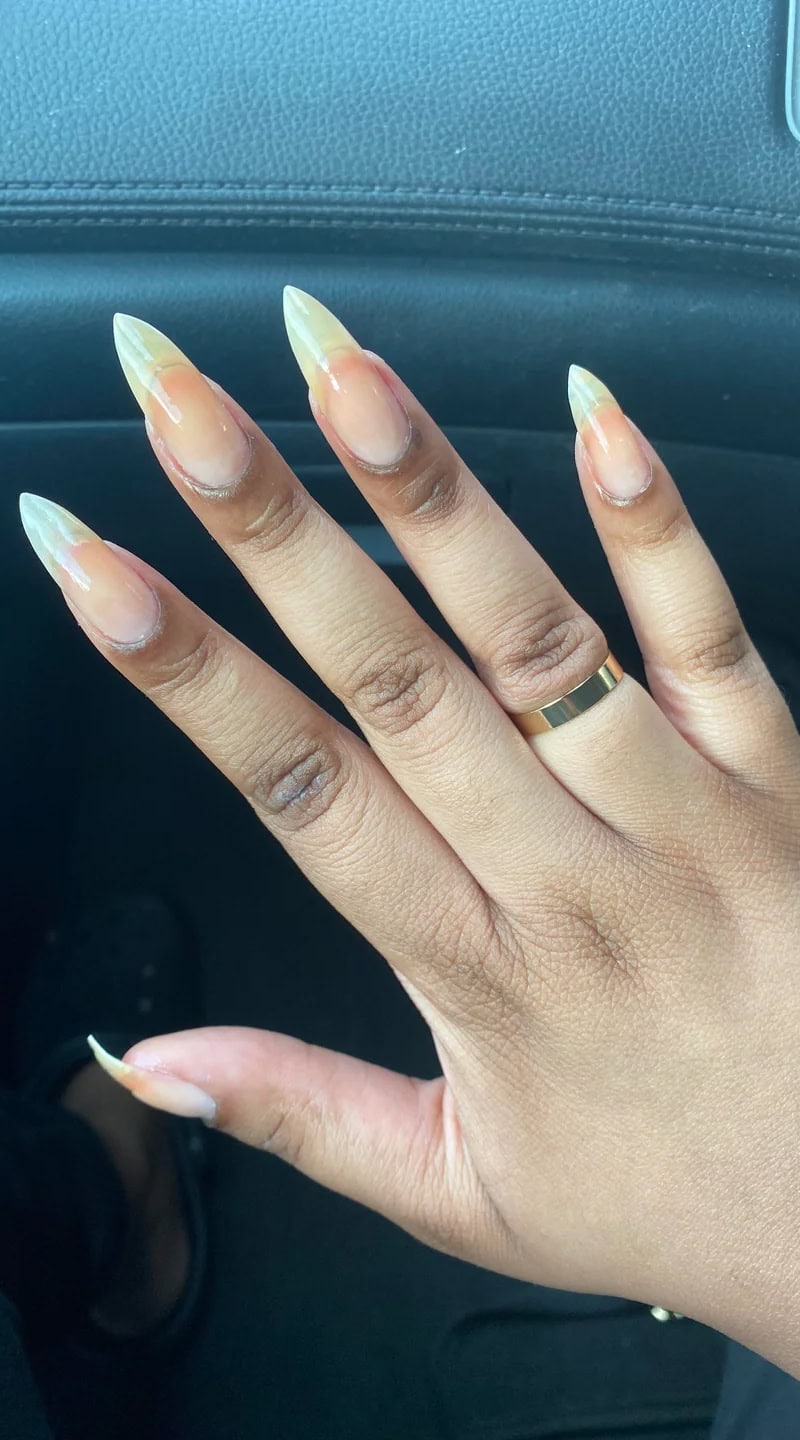 Hand with long, natural nails showing yellowing and thinning after recent gel polish removal.