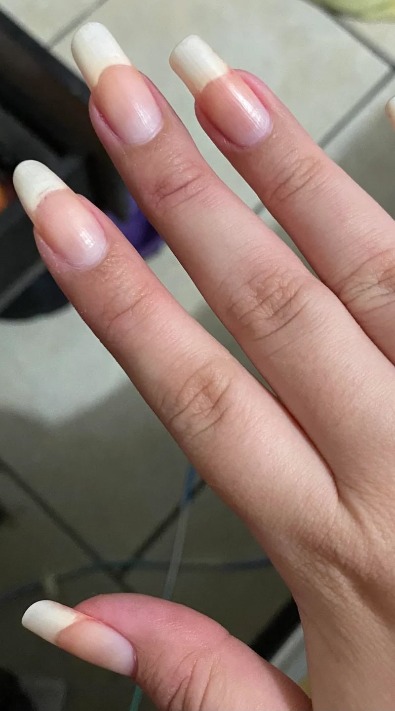 Long, natural nails with a slight almond shape shown without any polish on fair skin.