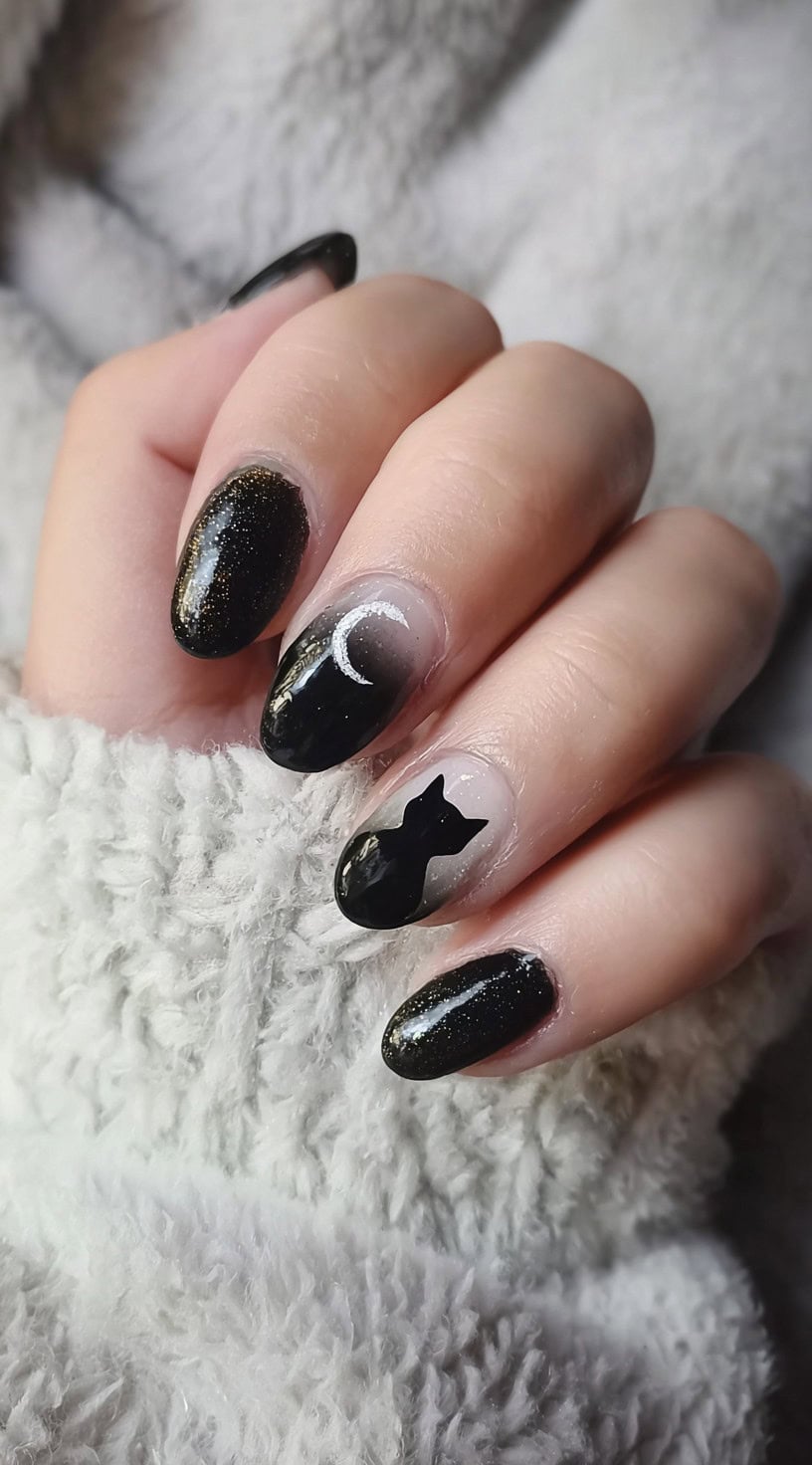 Medium almond-shaped nails with black gradient tips and accent nails featuring a silver crescent moon and a black cat silhouette.