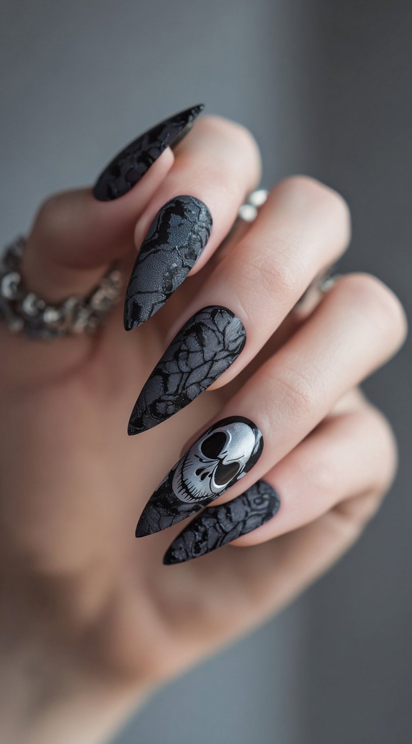 Hand with long black stiletto nails featuring matte black lace patterns and Jack Skellington's face accent nail.