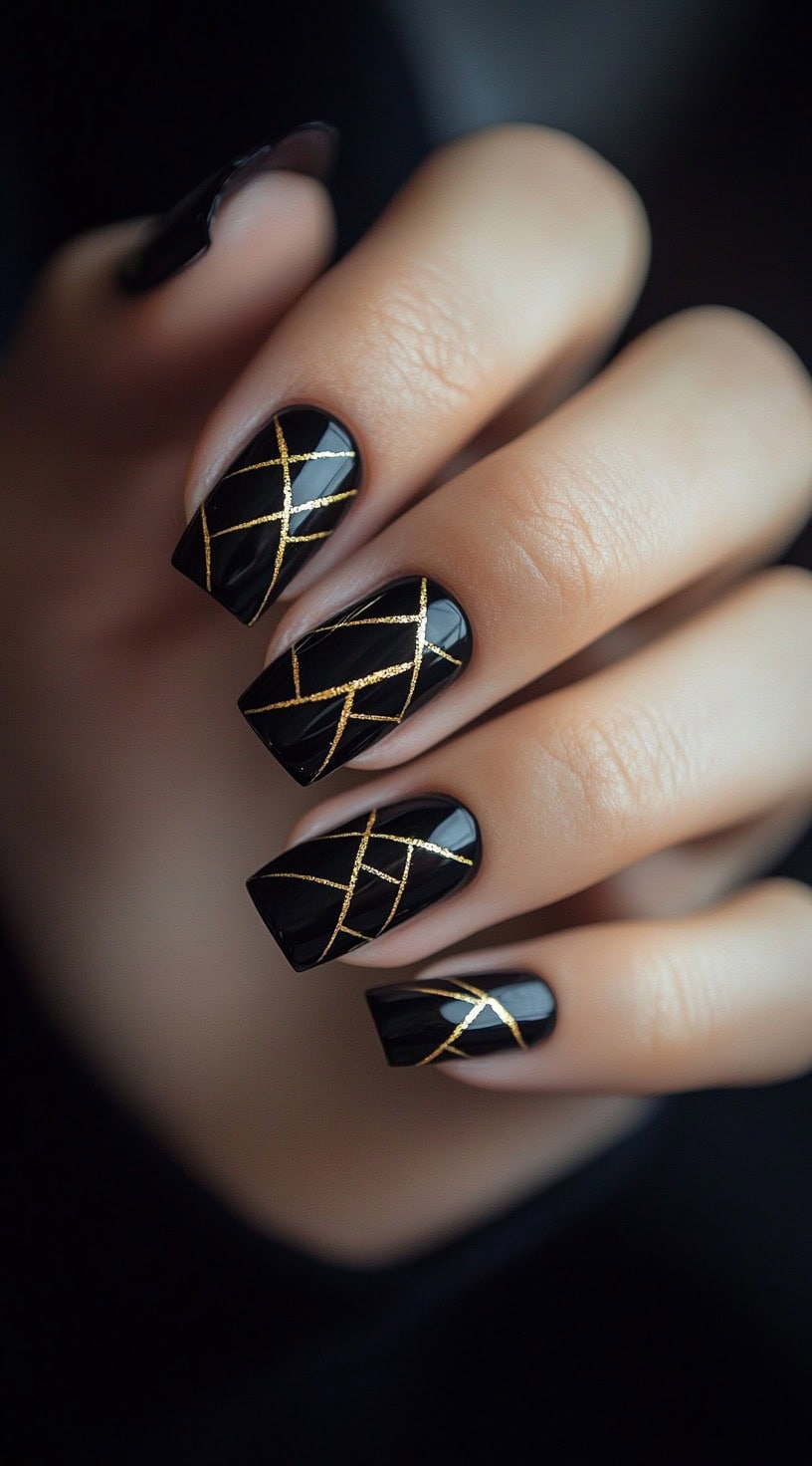 A hand with square-shaped black nails featuring delicate, intersecting gold lines for a geometric design.