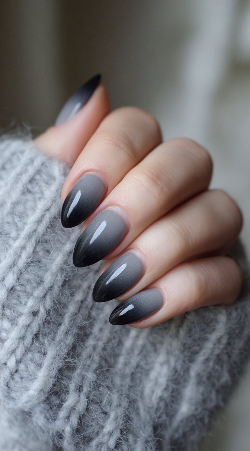 Almond-shaped nails with a seamless black-to-grey vertical ombre fade and a glossy top coat.
