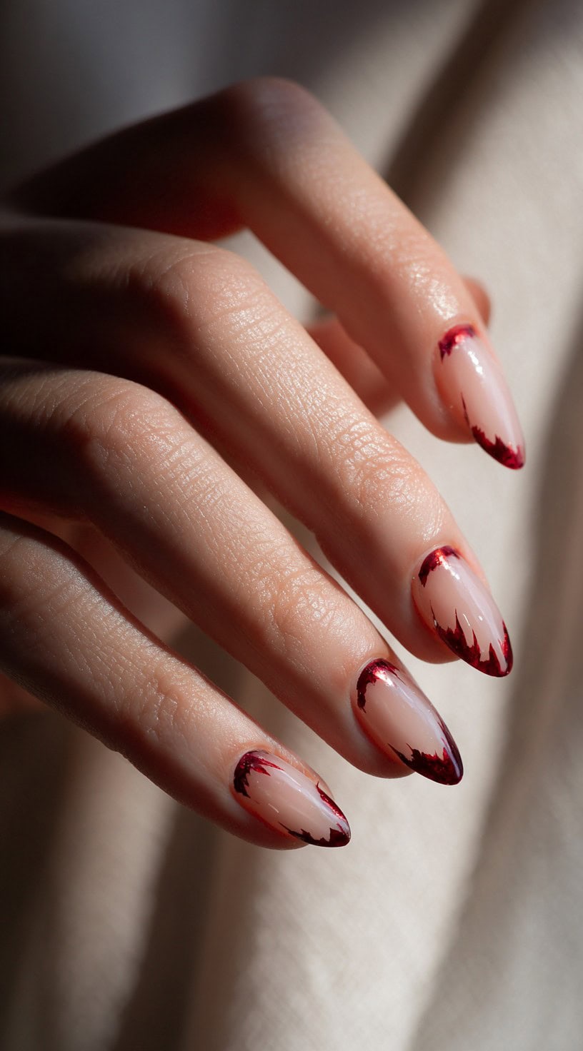 Almond-shaped sheer nude nails with crimson, blood-drip inspired tips.