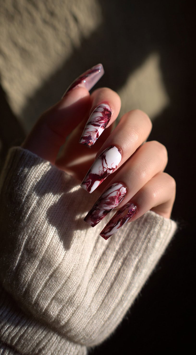 Long coffin nails with white and deep crimson marbling, mimicking swirling blood on a pale canvas.