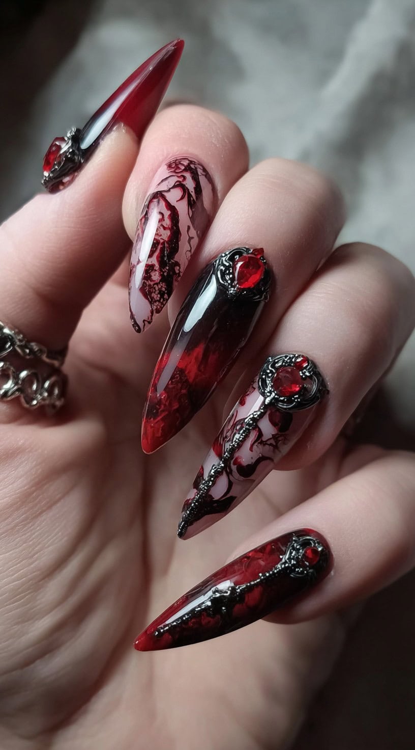 Long, pointed stiletto nails with black and deep red marbled designs accented by ornate red gemstones.