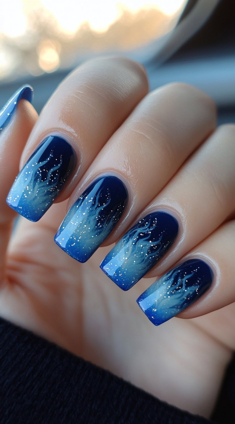 Square nails with a smoky blue ombre and glitter that resembles soft flames rising from the tips.