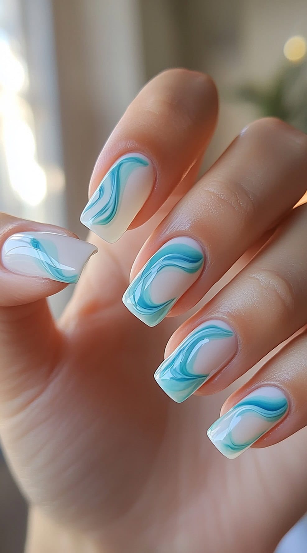 Square nails with a blue and white marble swirl design on a natural base.