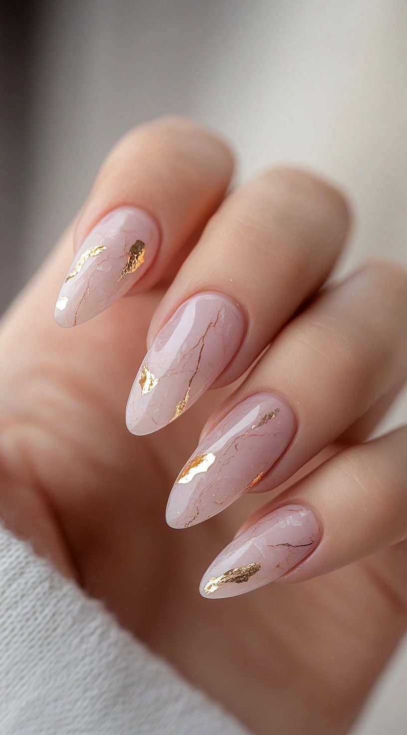 Almond-shaped blush marble nails with delicate gold foil streaks.