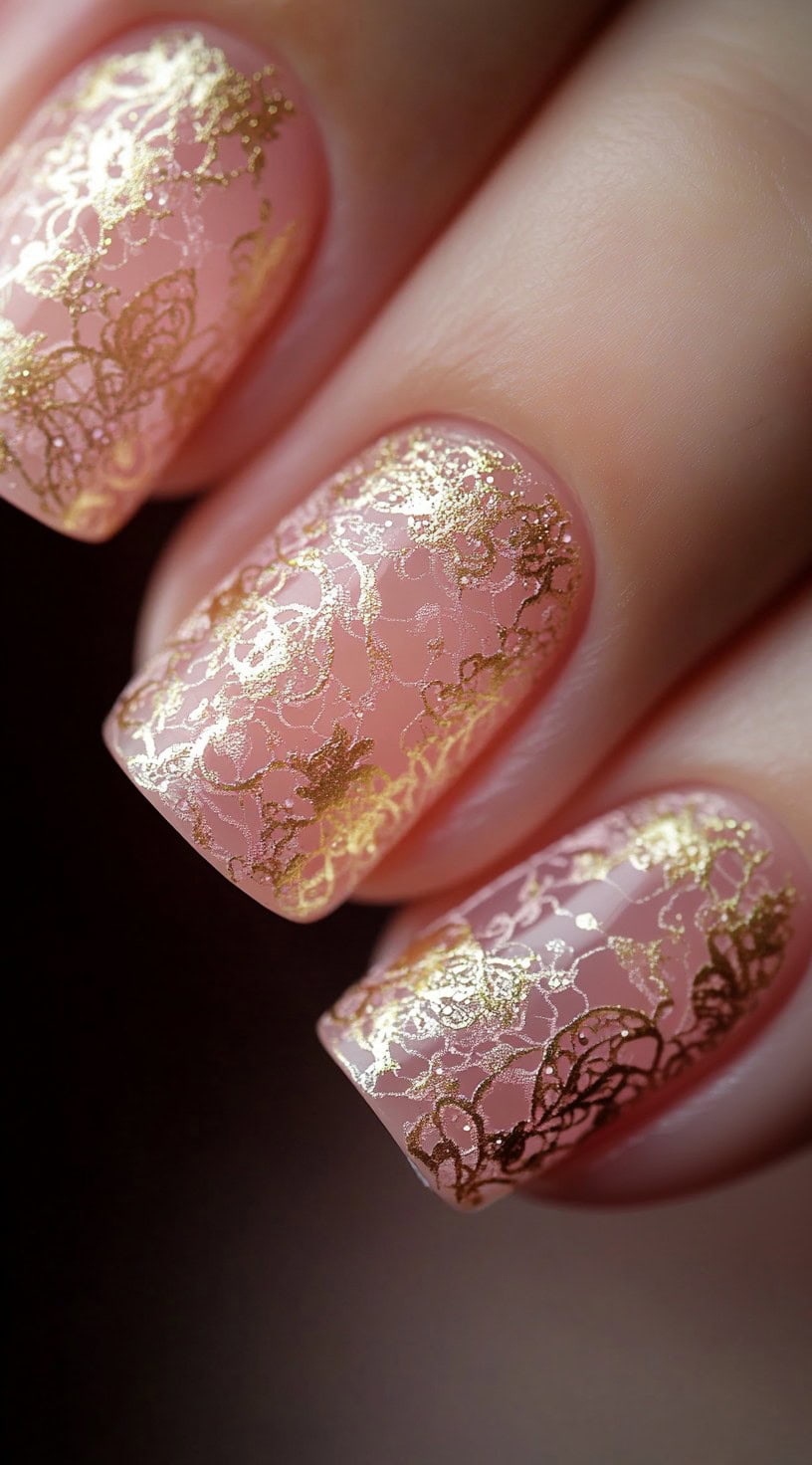 Short, square-shaped nails with a soft blush pink base and intricate gold lace patterns for a delicate and romantic look.