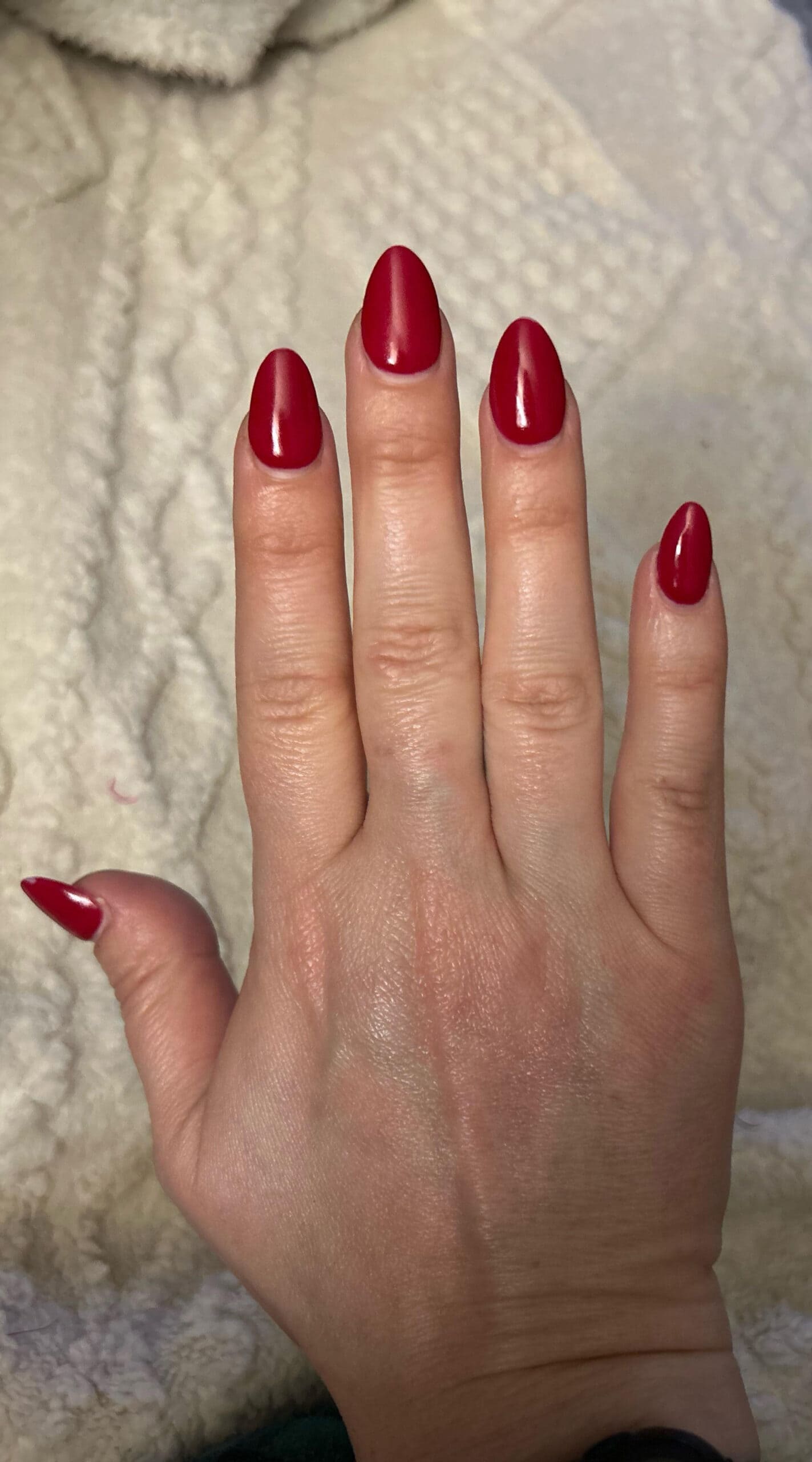 Bright red almond-shaped nails on a wider nail bed, showcasing a dramatic shape that elongates the fingers.