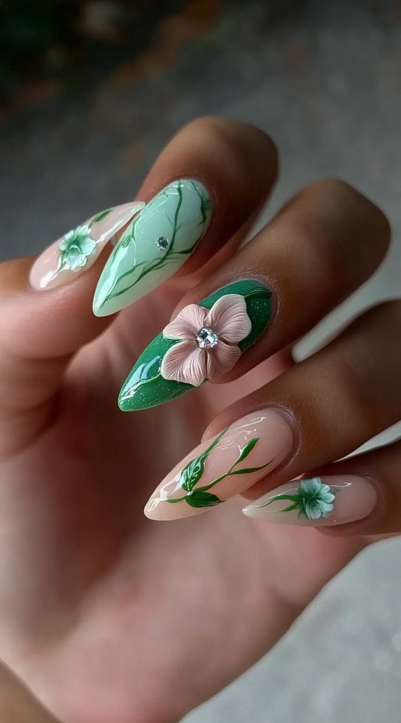A mix of green and clear nails adorned with 3D pastel flowers, vine-like detailing, and subtle gemstone accents.