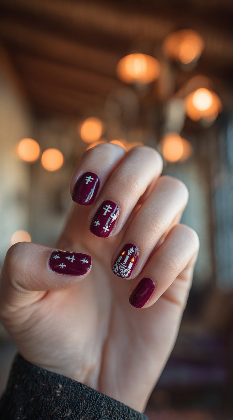 Burgundy nails with delicate white cross patterns and a single nail featuring an altar with glowing candles.