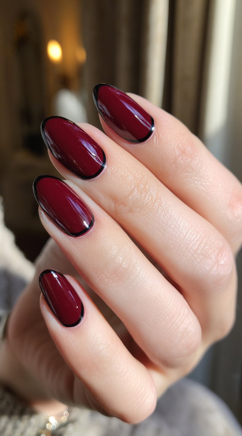 A hand with glossy deep wine nails precisely outlined in thin black borders.