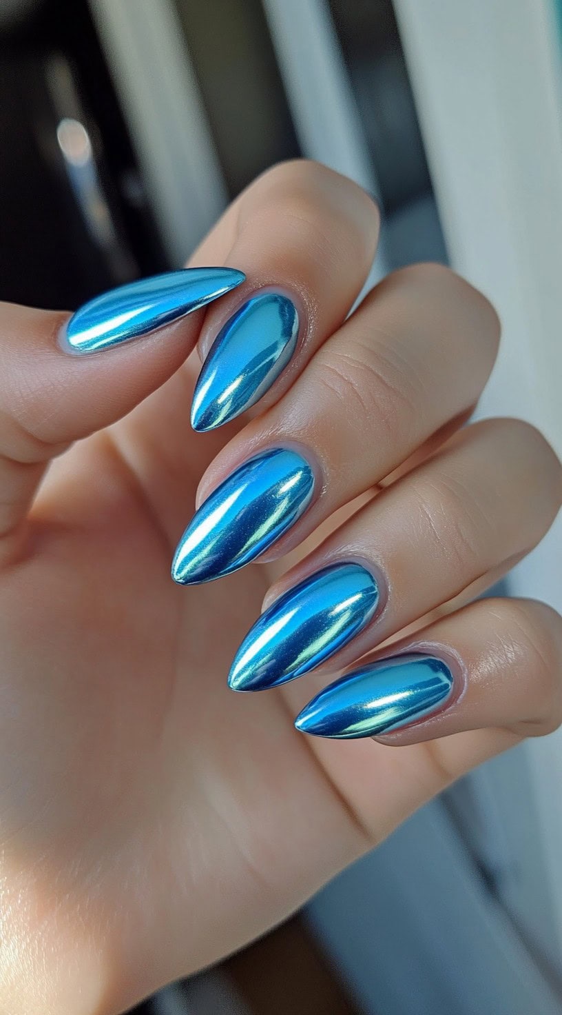 High-shine metallic blue almond nails with a mirror-like chrome effect.