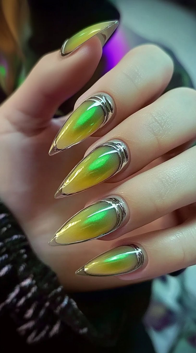 Sharp stiletto nails featuring a hypnotic green-to-gold cat-eye effect framed with reflective silver chrome accents.