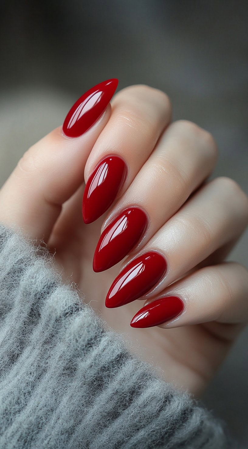 Glossy almond-shaped nails painted in a classic, vibrant red tone.