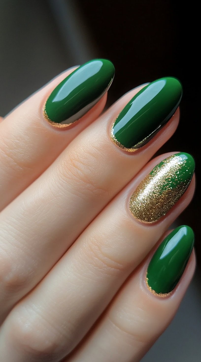 A set of almond-shaped nails in a rich, glossy green, highlighted with gold cuticle accents and a subtle touch of gold glitter.