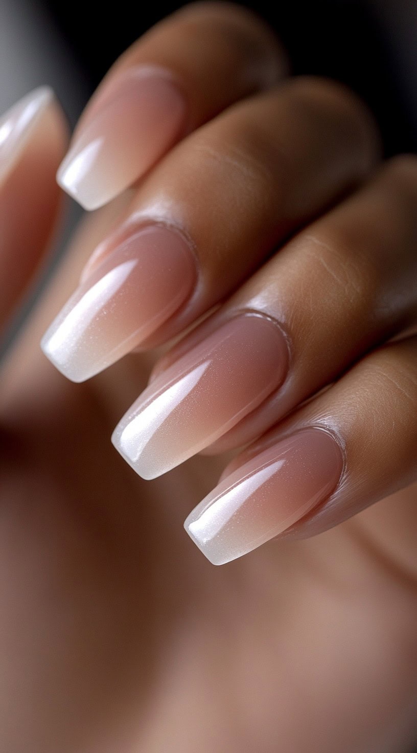 Long, square-shaped nails with a nude-to-white ombre finish and a subtle pearl sheen.