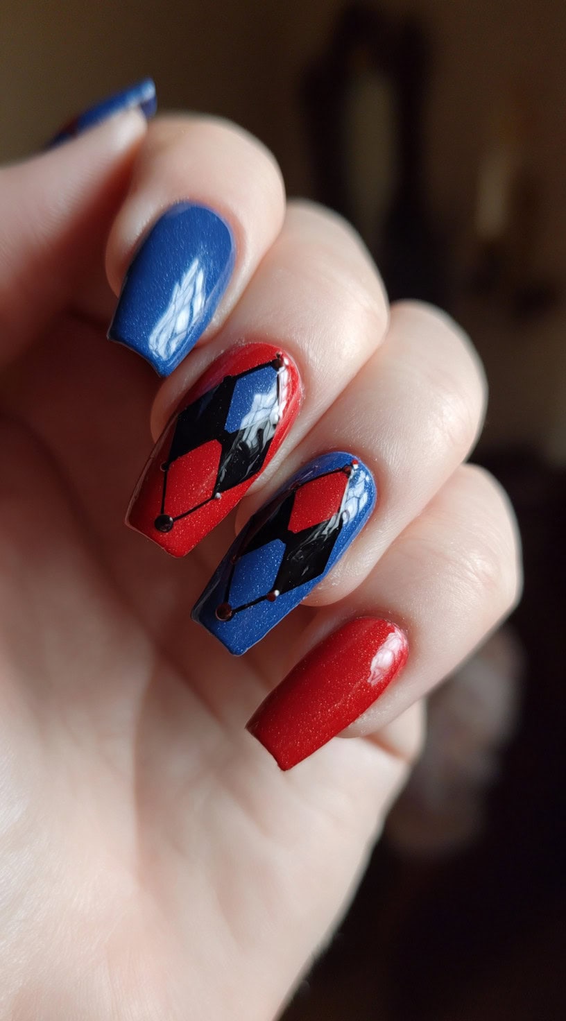 Square nails in alternating red and blue with black harlequin-style diamonds outlined with dotted accents on the middle fingers.