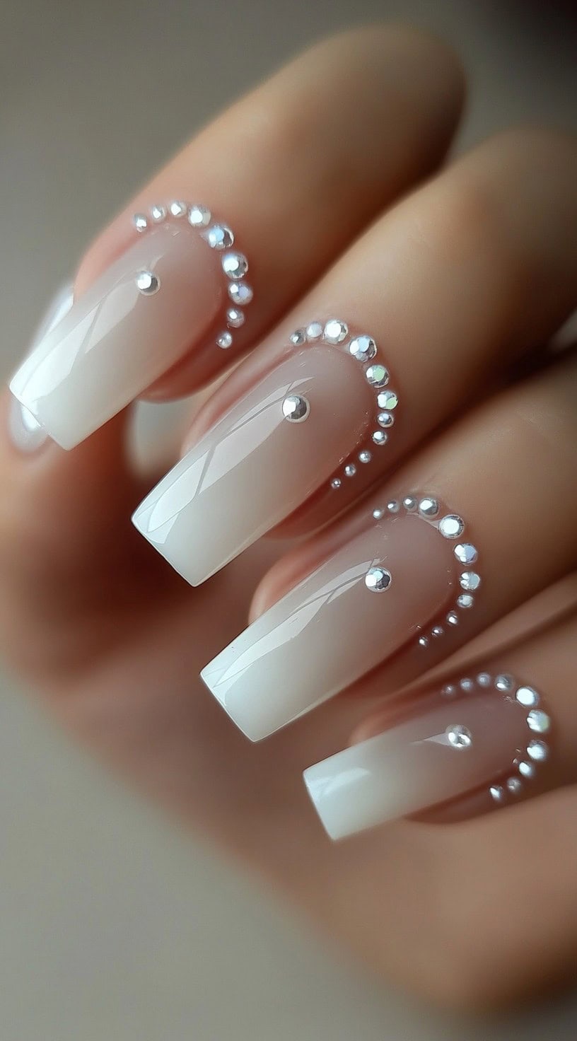 A set of white French square nails with a glossy finish, featuring rhinestone embellishments framing the cuticle area.