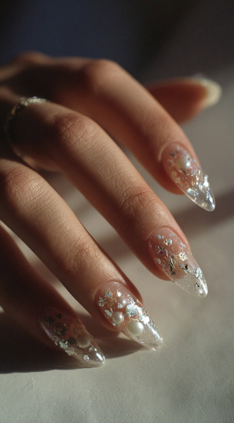 Almond-shaped clear nails featuring scattered silver foil flakes and varied-sized white pearls embedded throughout.