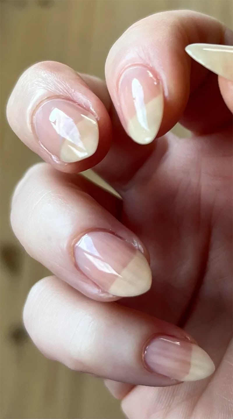 Glossy natural nails with an almond shape and a transparent nude polish finish on light skin.