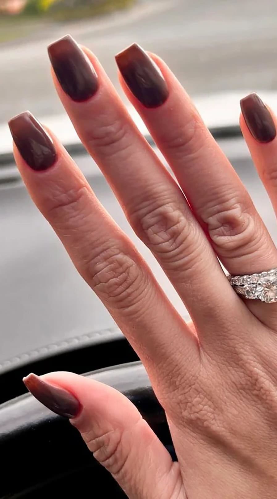 Long fingers with glossy dark coffin-shaped nails paired with a diamond ring.