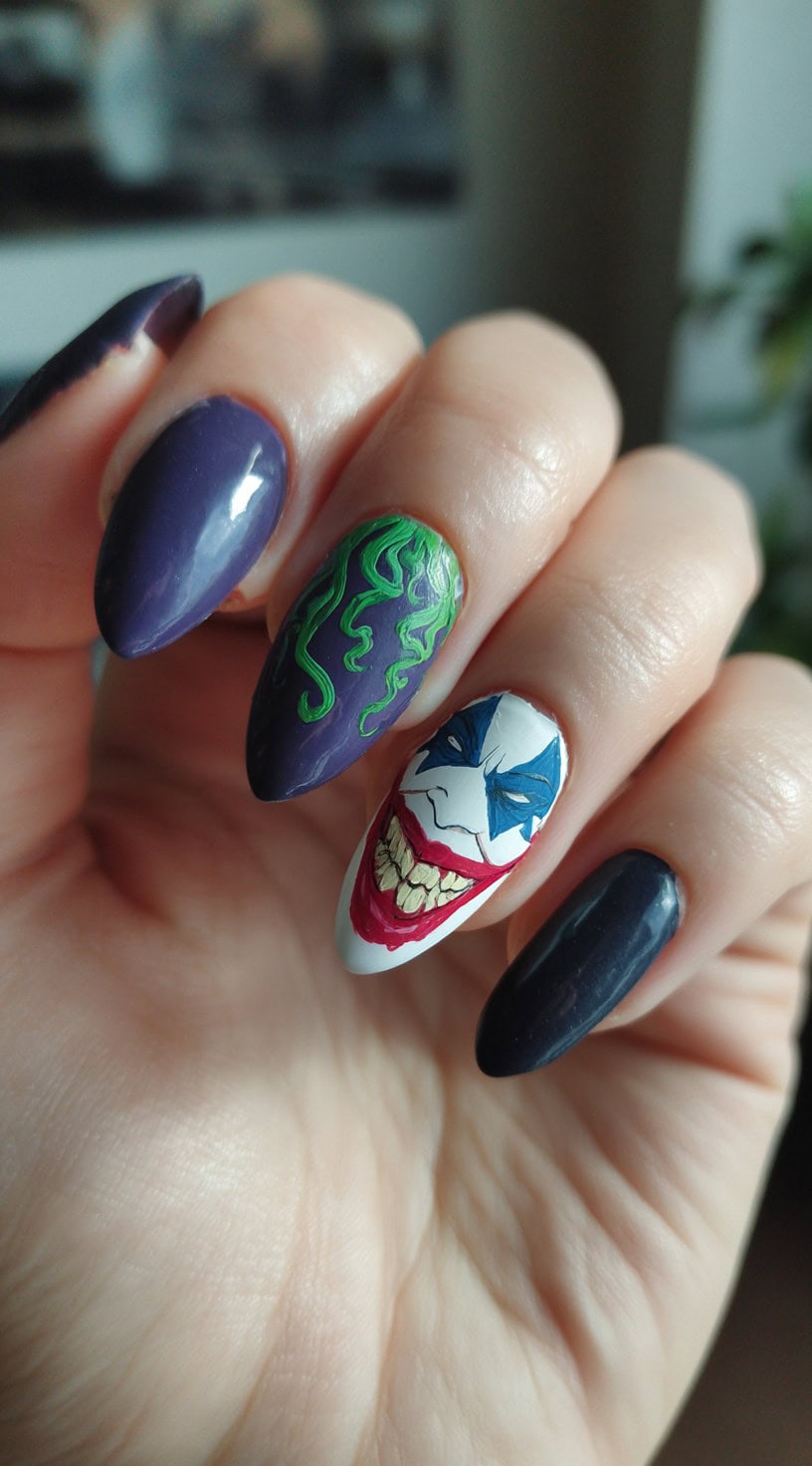 Almond-shaped nails with deep purple and black polish, featuring green flame detailing and a painted white accent nail with a wide, menacing grin.