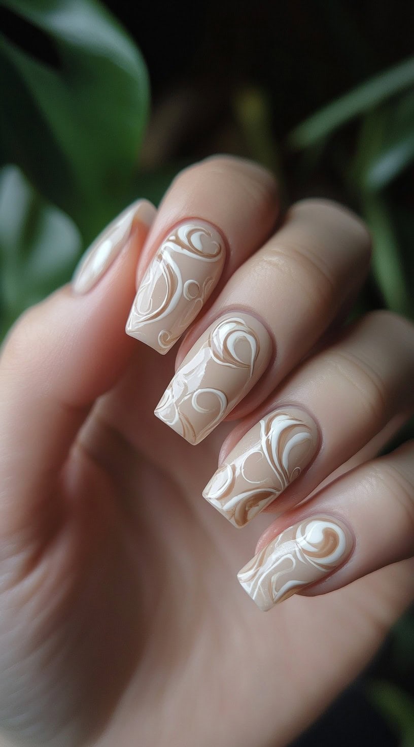 A close-up of nude-toned square nails featuring intricate white swirl designs for a soft and elegant wedding manicure.