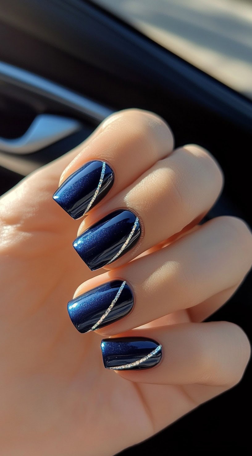 Short, square-shaped dark blue nails with fine diagonal silver glitter lines for a minimalist touch.