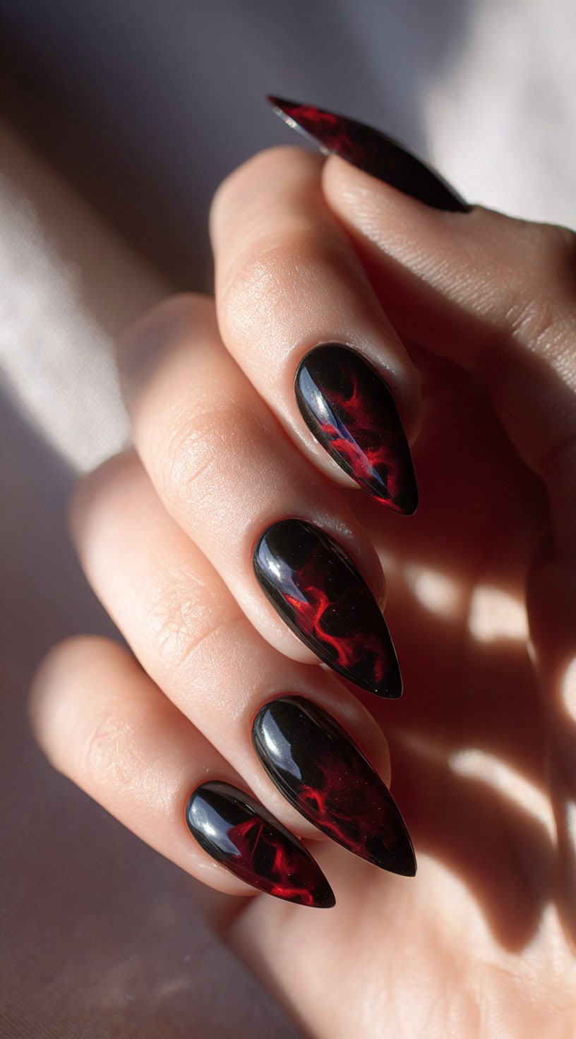 Long almond-shaped nails painted with a glossy black base and fiery crimson lightning patterns.