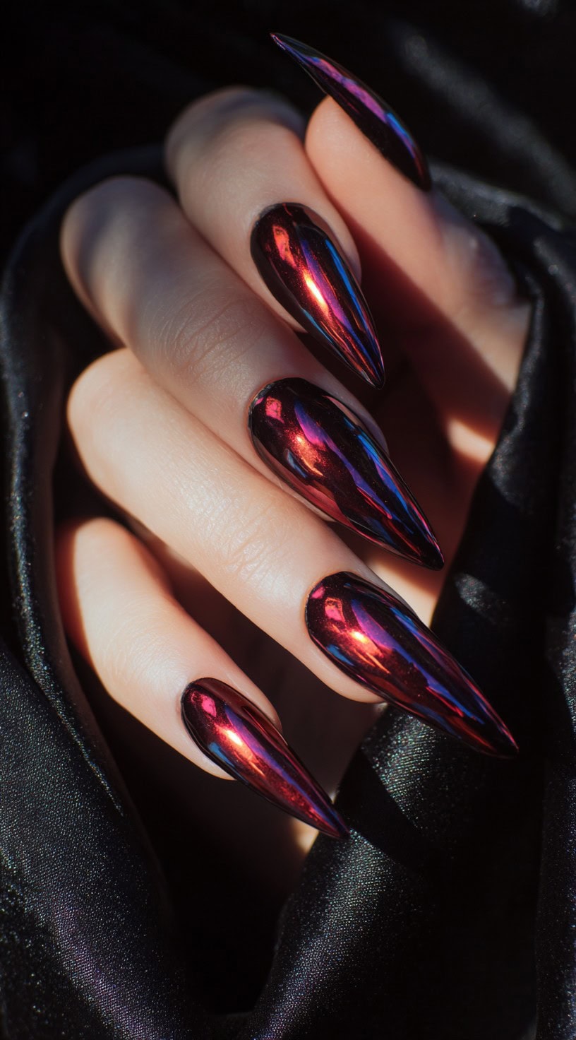 Almond-shaped nails coated in reflective dark ruby chrome for a molten metal effect.