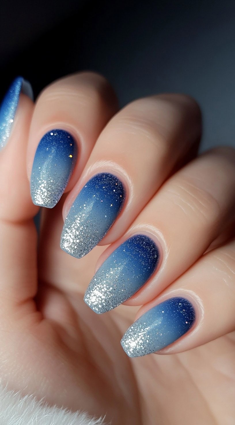 Oval nails with a bold blue-to-silver ombre effect and micro glitter for a starry-night finish.