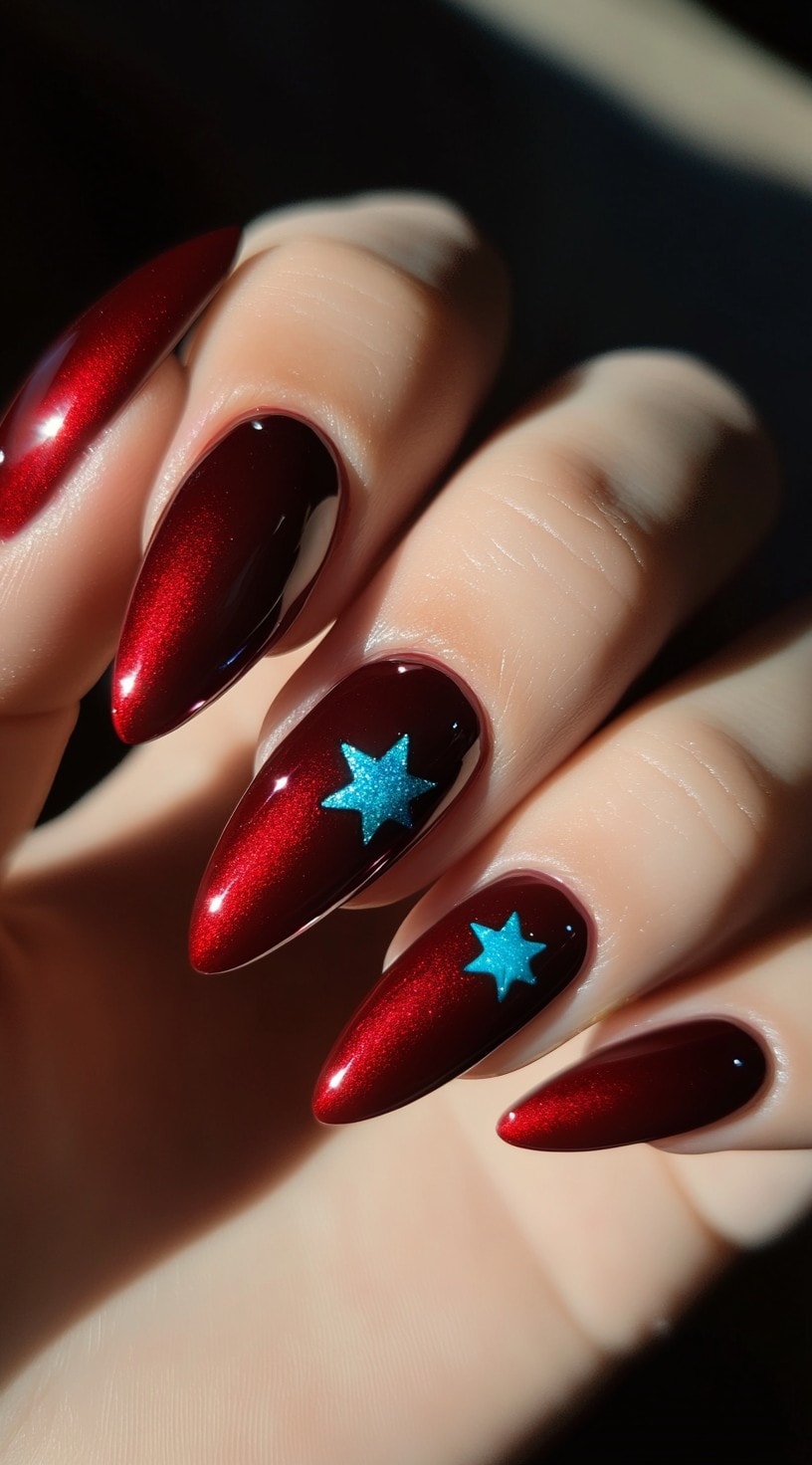 Shiny deep red almond-shaped nails with bright blue star accents on two fingers.