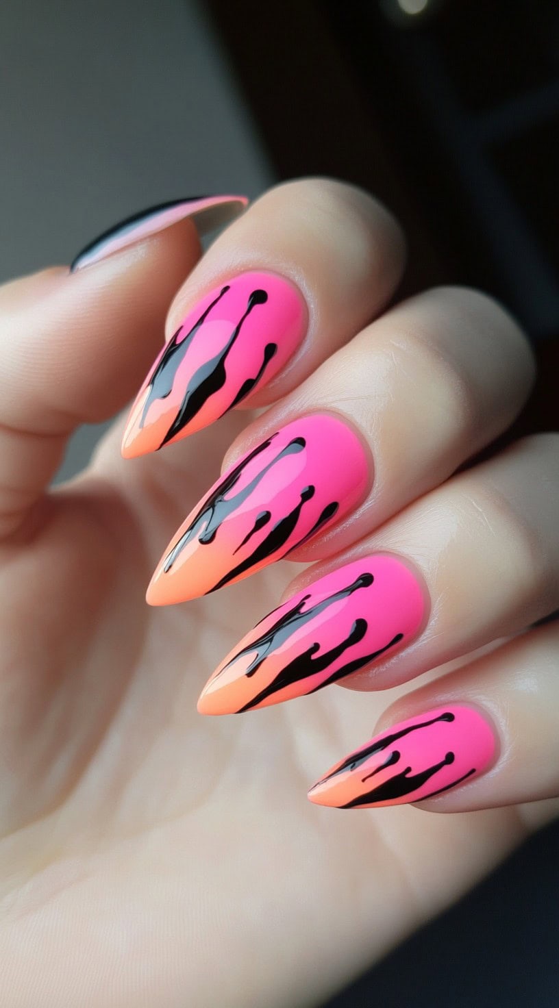Stiletto nails with a pink-to-orange ombre base topped with black dripping flame designs that run from tip to cuticle.