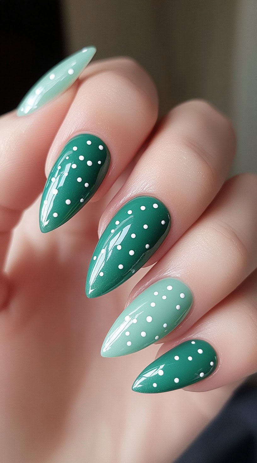 Glossy stiletto-shaped nails featuring a split design with deep green and mint green tones, accented with small white polka dots.