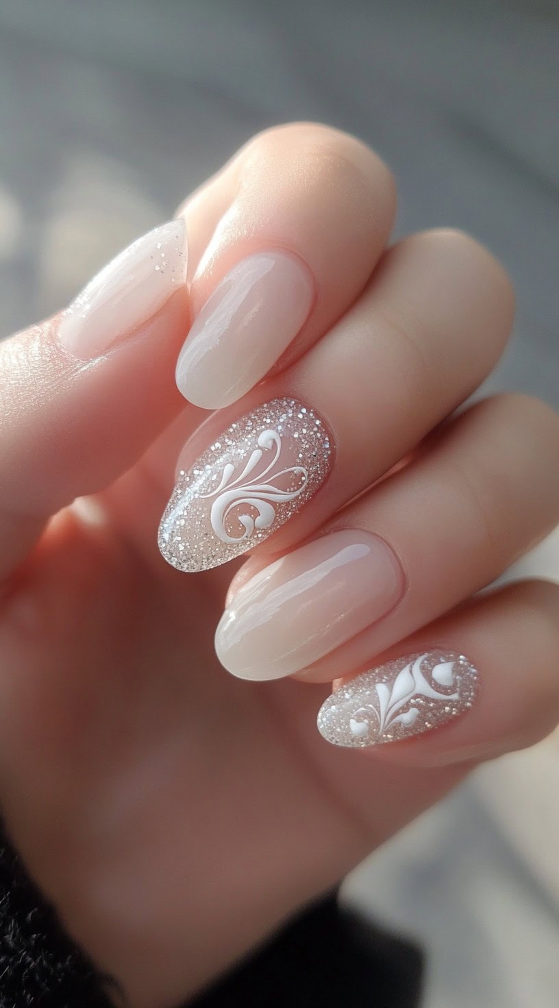 A close-up of a bride's hand with short almond-shaped nails featuring a nude-pink base, silver glitter accent nails, and intricate white lace designs.