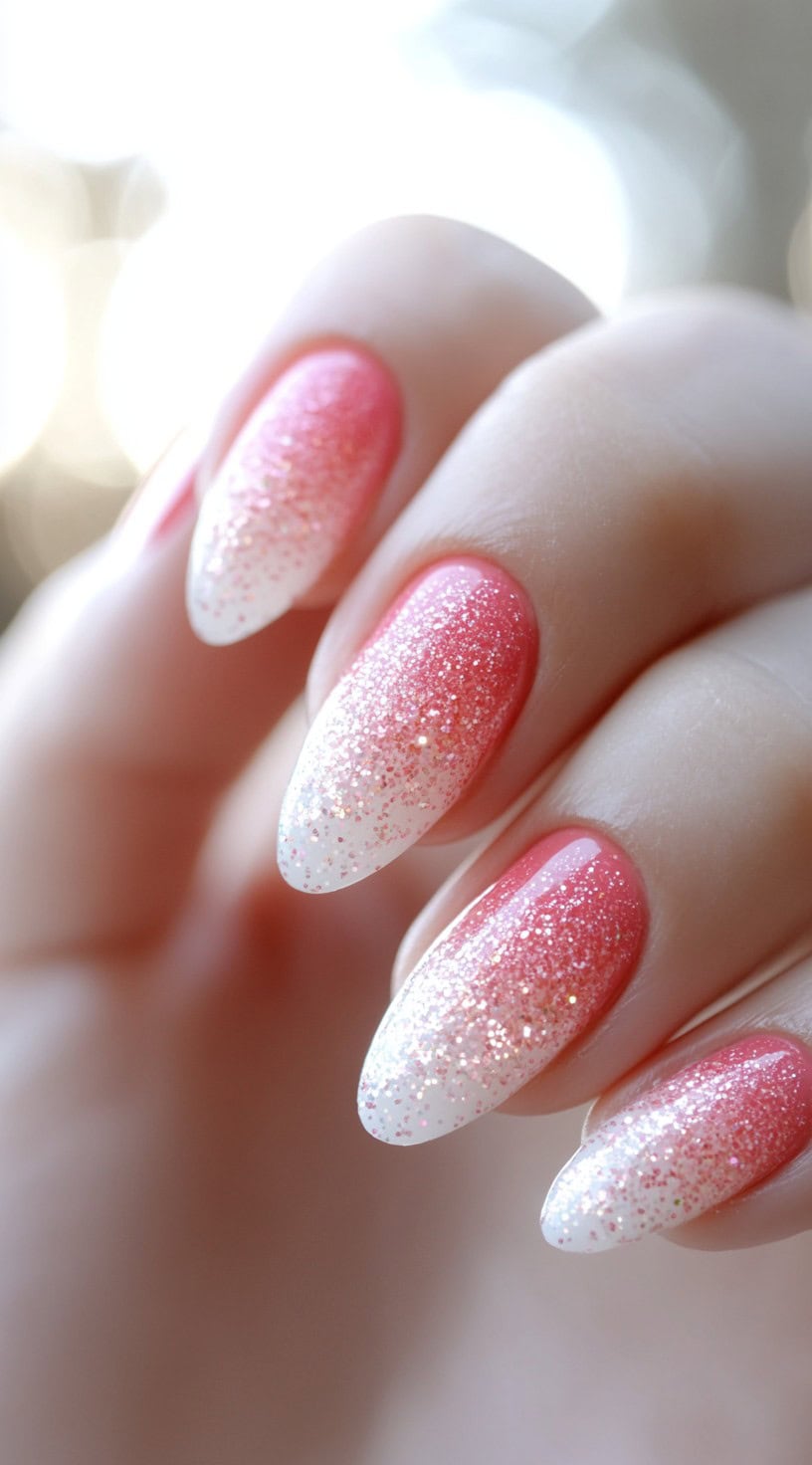 Almond nails with a vibrant pink base fading into white tips, layered with iridescent glitter for a frosted finish.