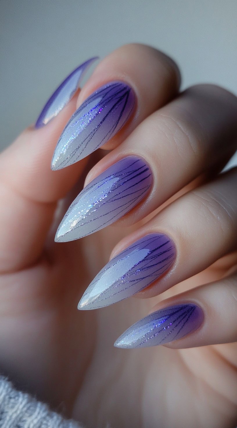 Almond nails featuring a lavender ombre base and thin, linear purple glitter veining over top.