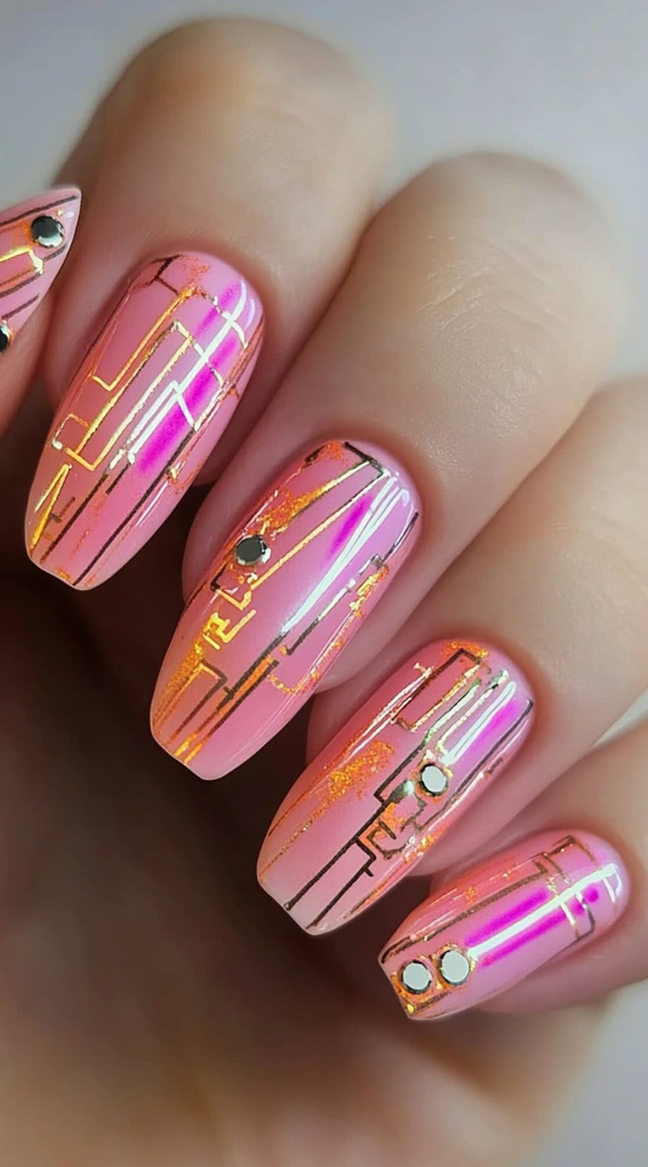 Medium almond nails in a pink and orange foil base overlaid with shiny metallic circuitry lines and crystal studs.