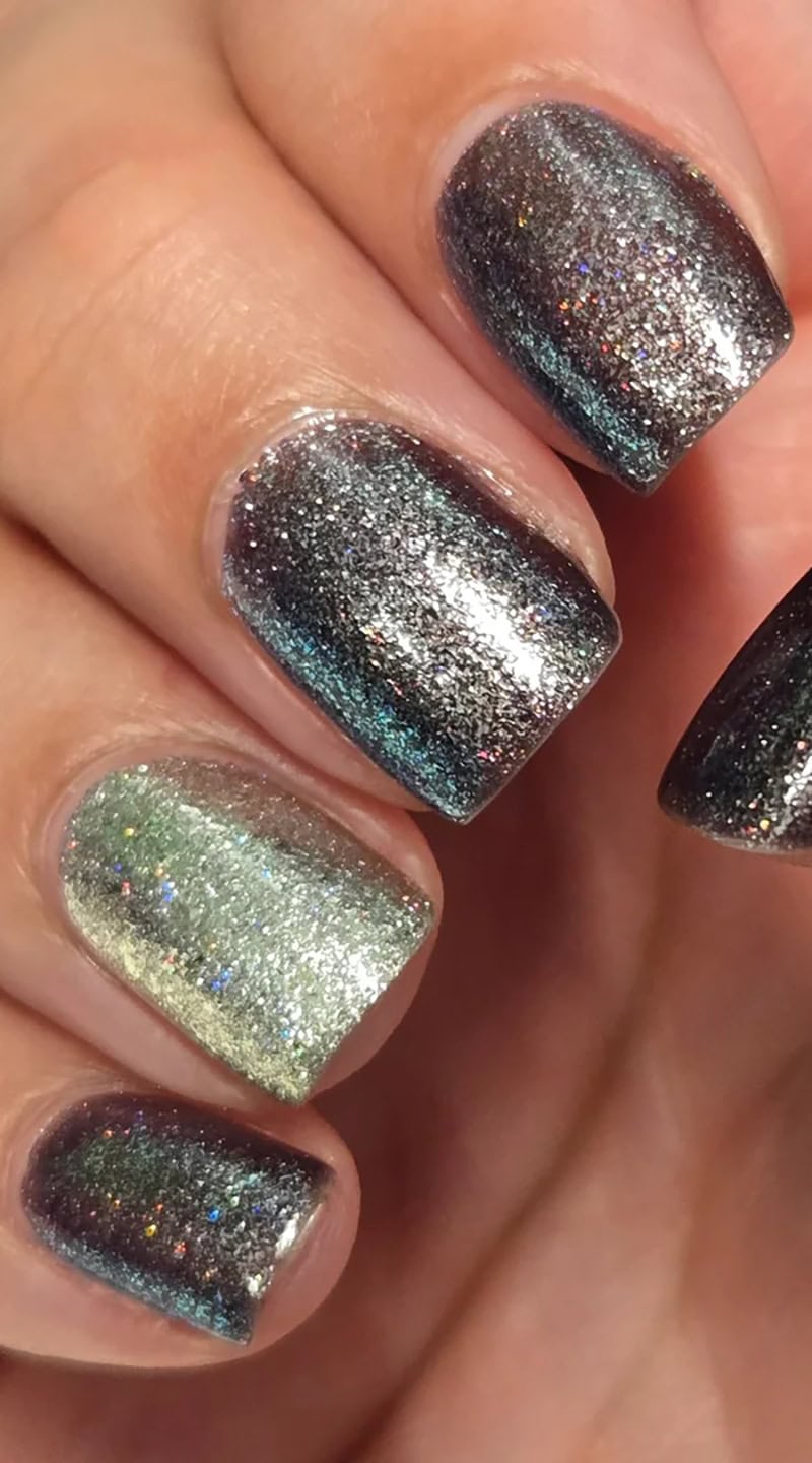 Close-up of nails painted with chunky silver and black glitter polish catching the light with a metallic shimmer.