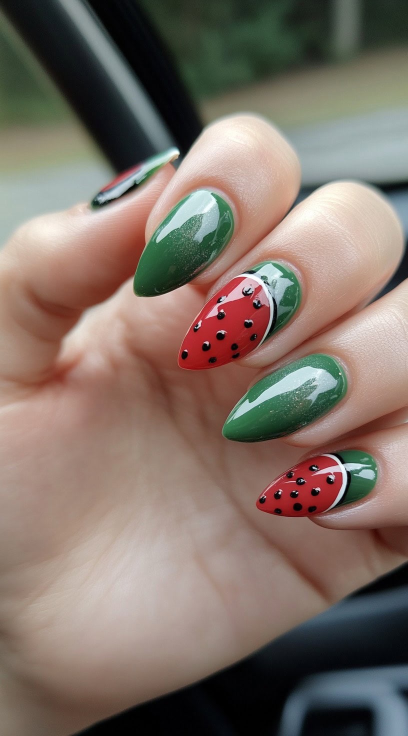Short almond nails with deep green polish and glossy red watermelon slices with 3D black seed dots.